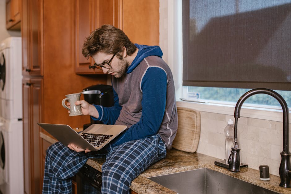 A person watching an educational video on a laptop with a notebook nearby.